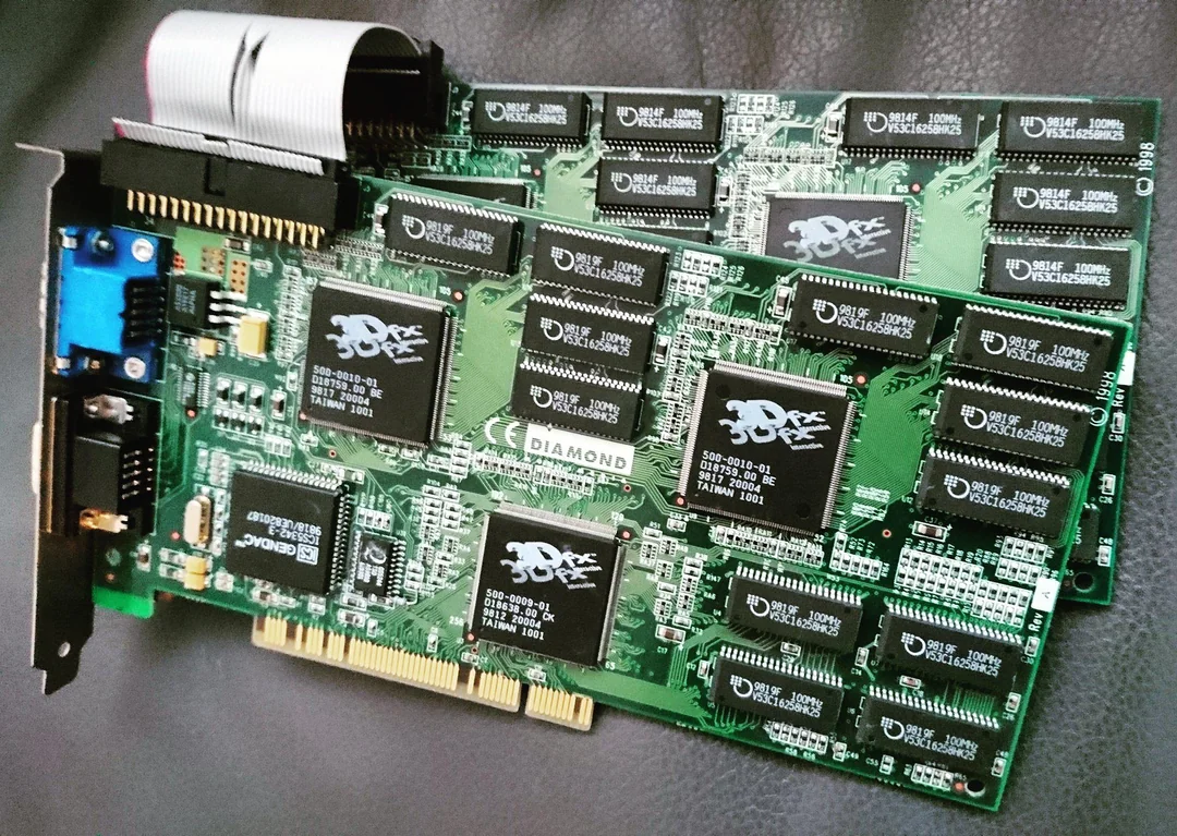Two vintage late-1990s PCI 3D accelerator cards on a dark surface, linked by a short ribbon cable like a Voodoo 2 SLI pair