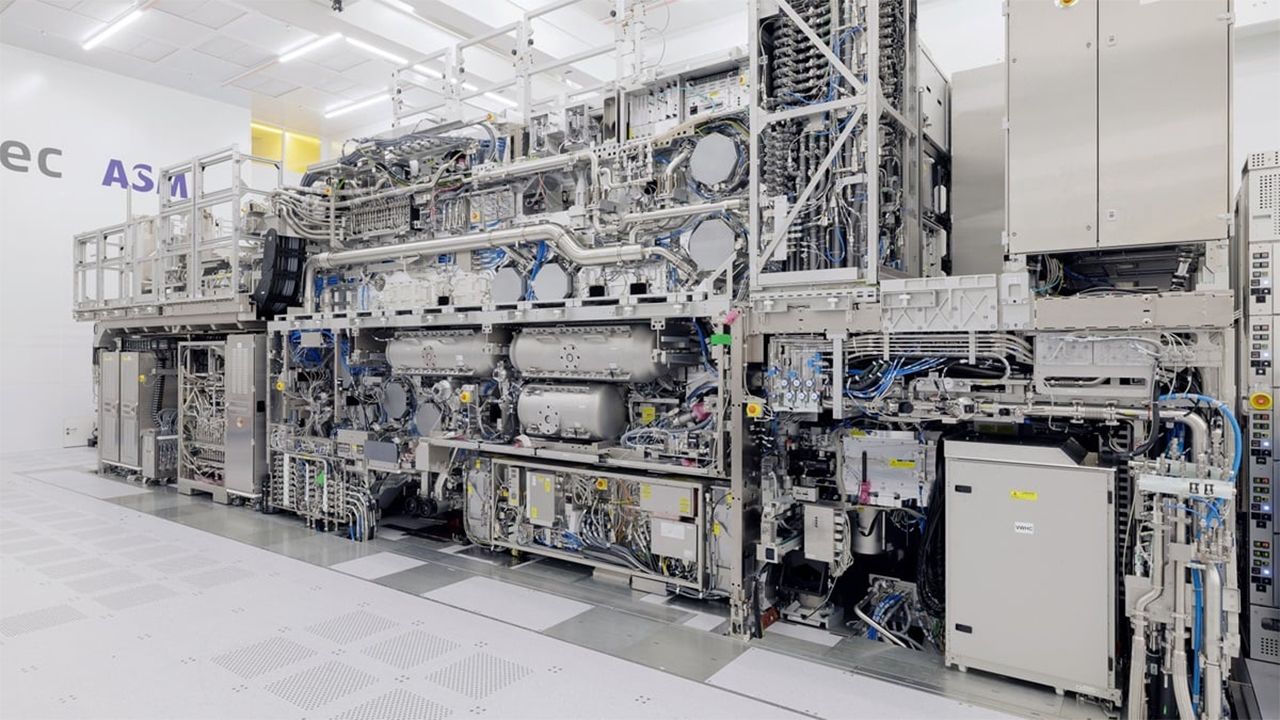 An ASML EUV lithography machine, roughly the size of a school bus, with its side panels open to reveal the internal optics and modules.