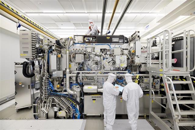 An ASML extreme ultraviolet lithography machine with technicians beside it, the tool China is barred from buying.